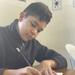 Un garçon qui écrit en classe.