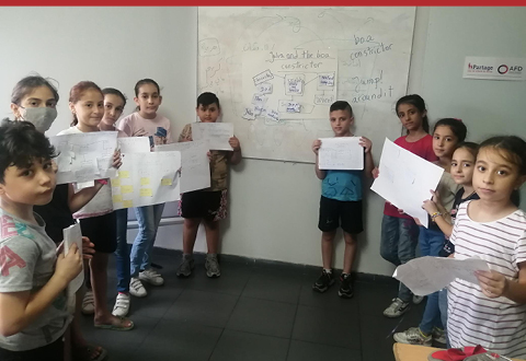 Enfants bénédiciaires du projet "Solidarité Liban" dans une classe qui tiennent une feuille devant un tableau