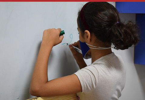 Jeune fille bénéficiaire du soutien scolaire du projet "Solidarité Liban" en train d'écrire sur un tableau.